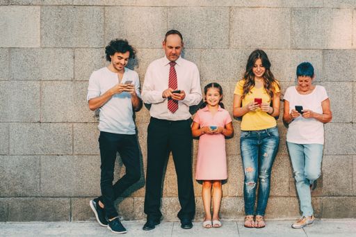 family-standing-against-wall-with-phones-in-hands