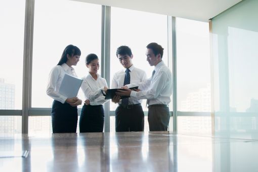 Four Young business people standing by conference table