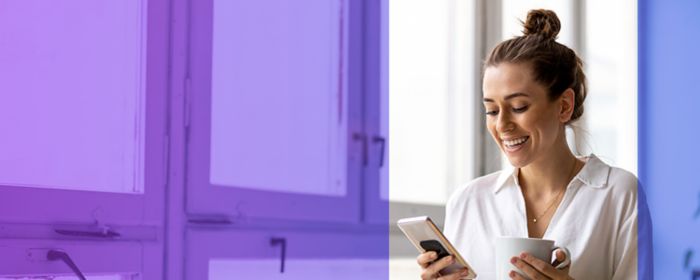 Frau mit Handy und Tasse in der Hand