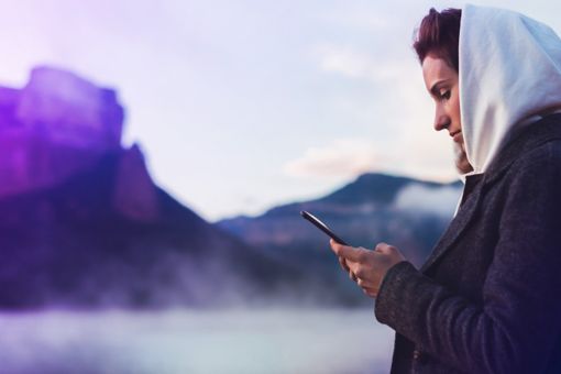 Woman with smartphone standing in front of mountains