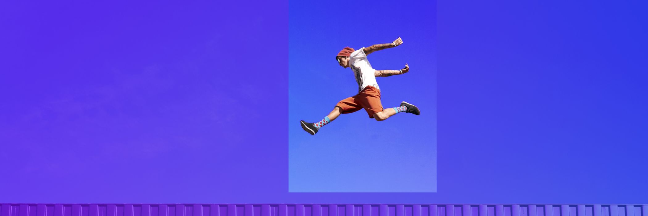 freerunner jumping on red container in front of blue sky