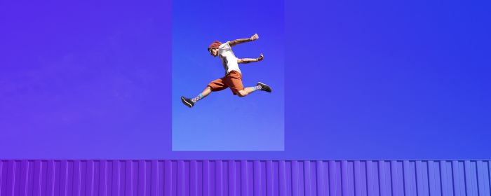 freerunner jumping on red container in front of blue sky
