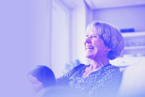 A laughing grey-haired woman relaxes in her home