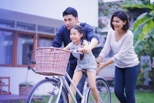 自転車に乗る子供を支える家族