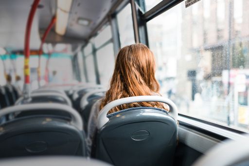 Girl sitting alone in bus looking outside window