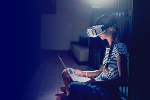 Girl wearing virtual reality goggles using laptop