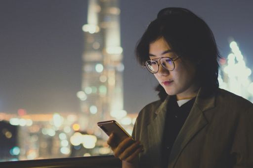 Girl wearing spectacles looking at mobile at night