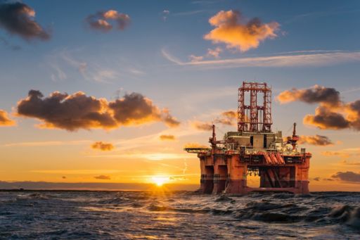 Sunrise behind an oil rig in ocean