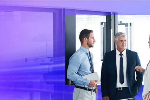 three standing professionals holding a conversation