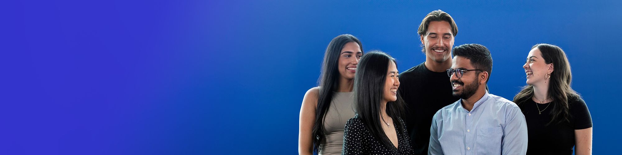 Smiling graduates against a pink background