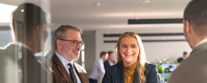 Tvær konur sitja við fundarborð og horfa brosandi í átt að myndavélinni