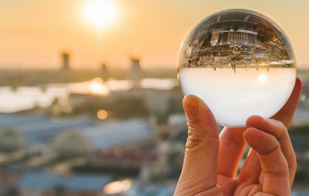 Cropped Image Of Hand Holding Crystal Ball Against City