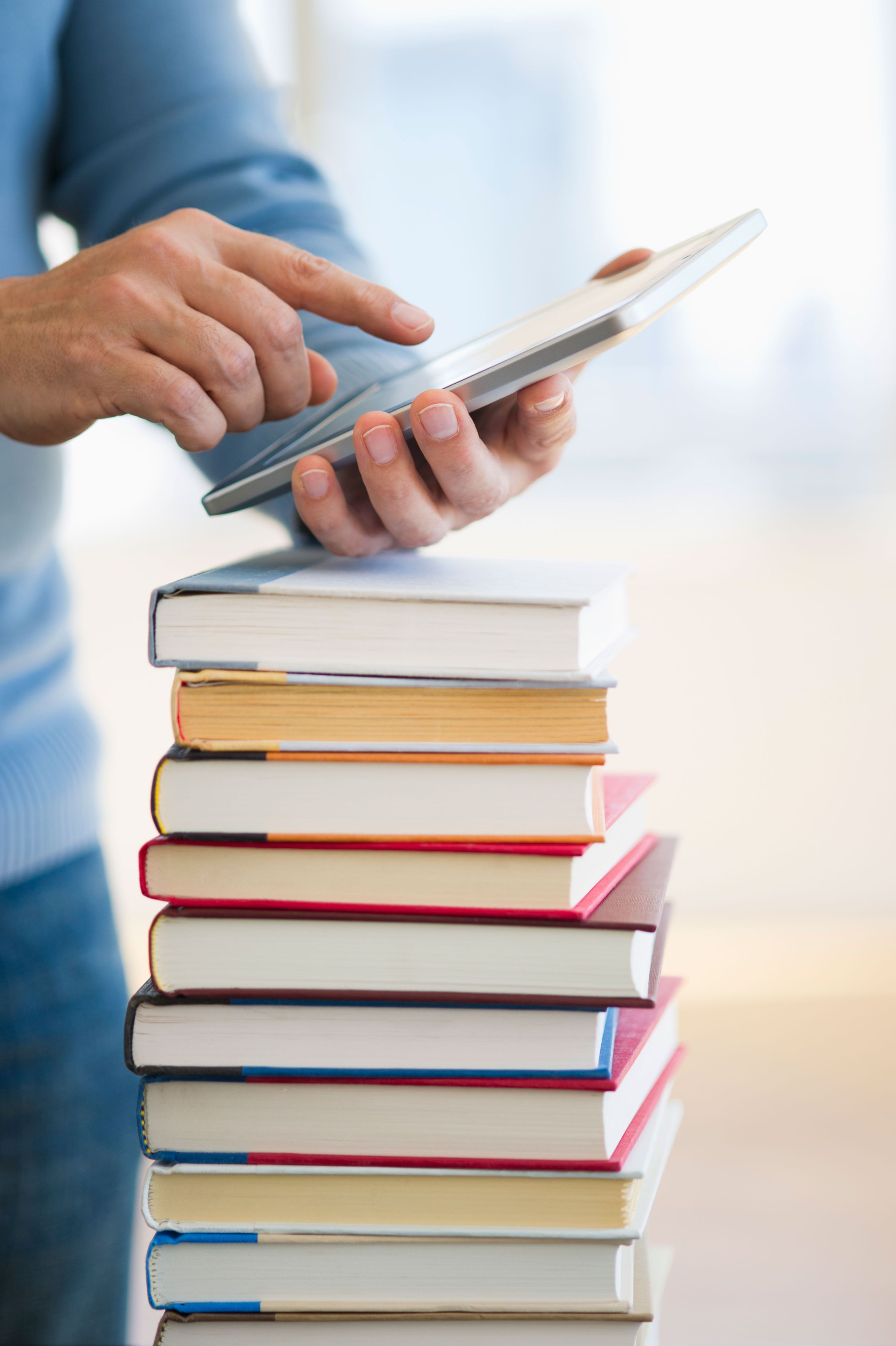 man using a smartphone with a stack of books