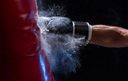 Hand in boxing glove punching sand bag
