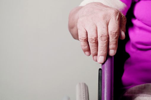 Older person in a wheelchair with hand resting on wheel