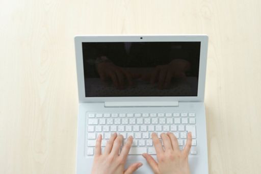 Hands on keyboard of white laptop