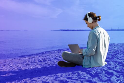 Persona en una playa trabajando en su laptop