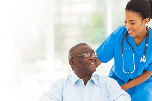 nurse looking at a elderly man sat in a chair