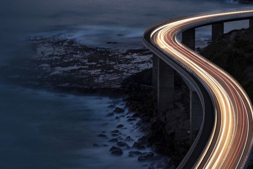 Highway mit Lichtspur der Autos am Meer