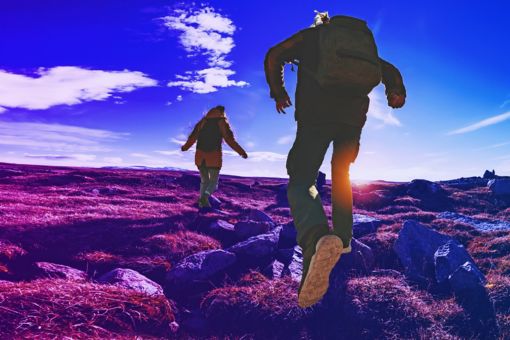Hikers running through rough terrain