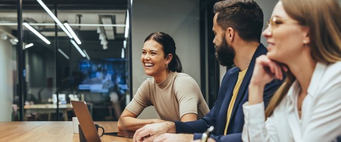Happy businesswoman laughing while leading a meeting with her colleagues. Group of diverse businesspeople working together in a modern workplace. Business colleagues collaborating on a project.