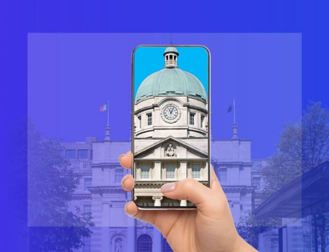 Hand holding smartphone displaying Irish government buildings