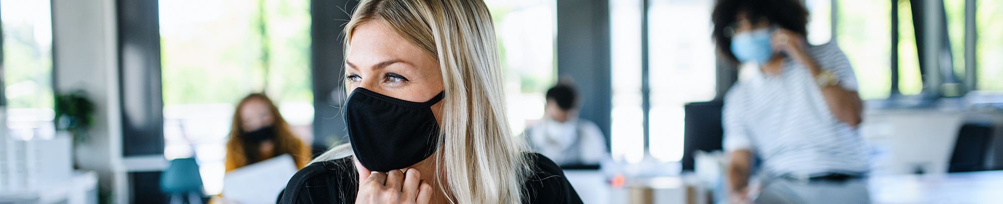 Woman wearing mask in open plan office