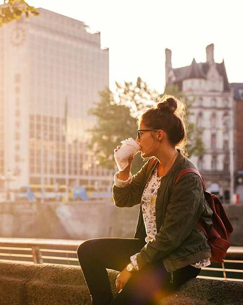 Woman drinking coffee beside the river Liffey in Dublin