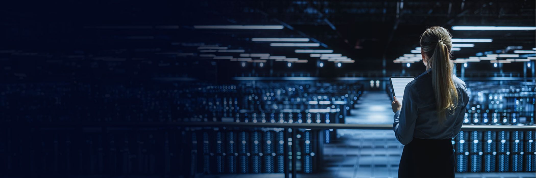 Woman looking over rows of servers in data centre