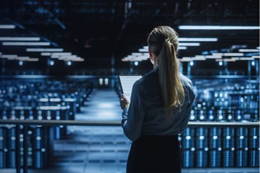 Woman looking over rows of servers in data centre