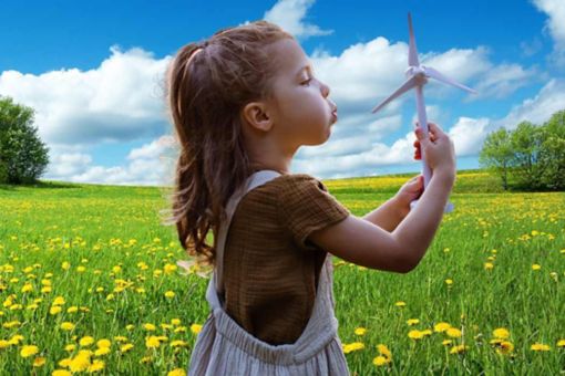 Girl holding toy wind turbine in field of flowers