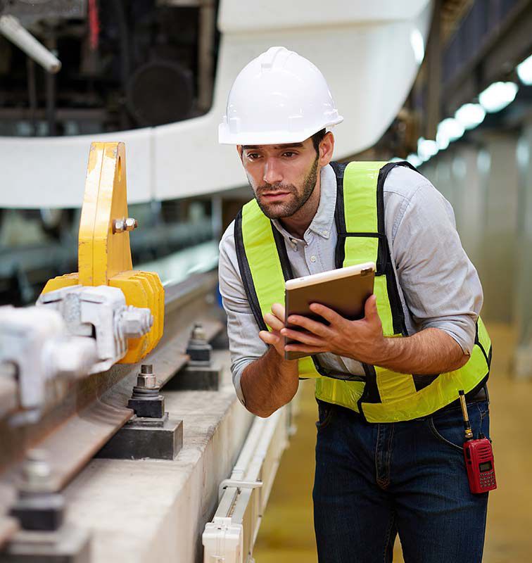 Technician or worker working on tablet and checking railroad track at construction train station