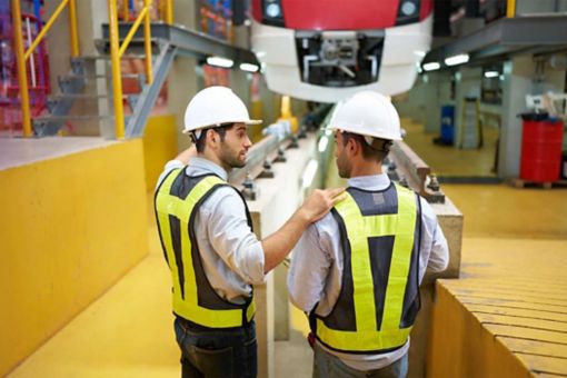 back view engineer talking and looking at high-speed rail or train at construction site