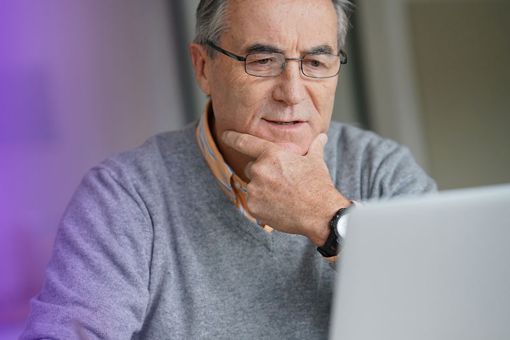 Man using laptop with pencil in hand