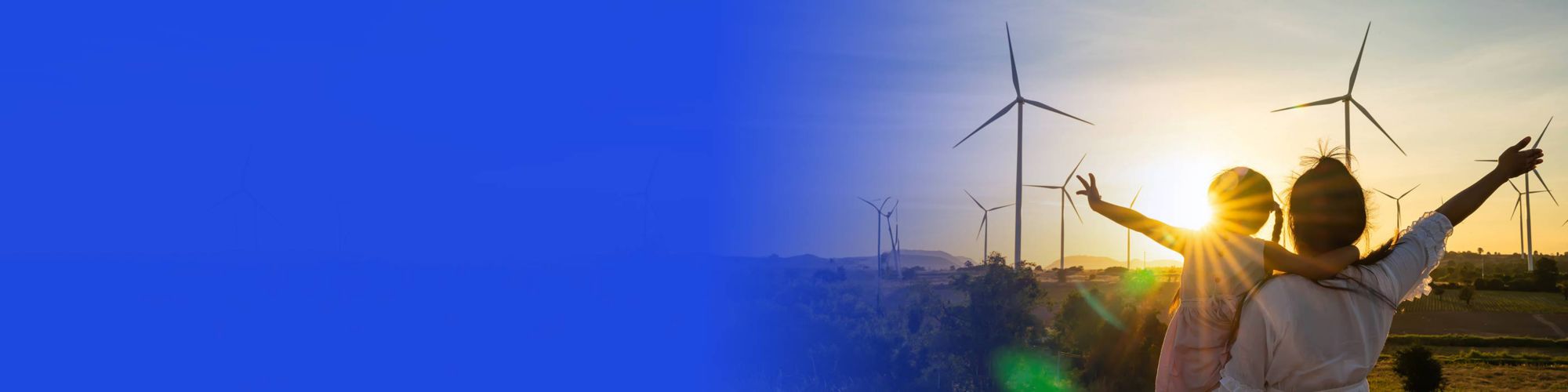 Woman and child in field looking at wind turbines