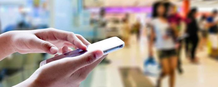 Hand holding smartphone in shop