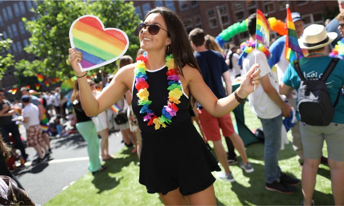 Woman holding rainbow heart and flag at KPMG Pride