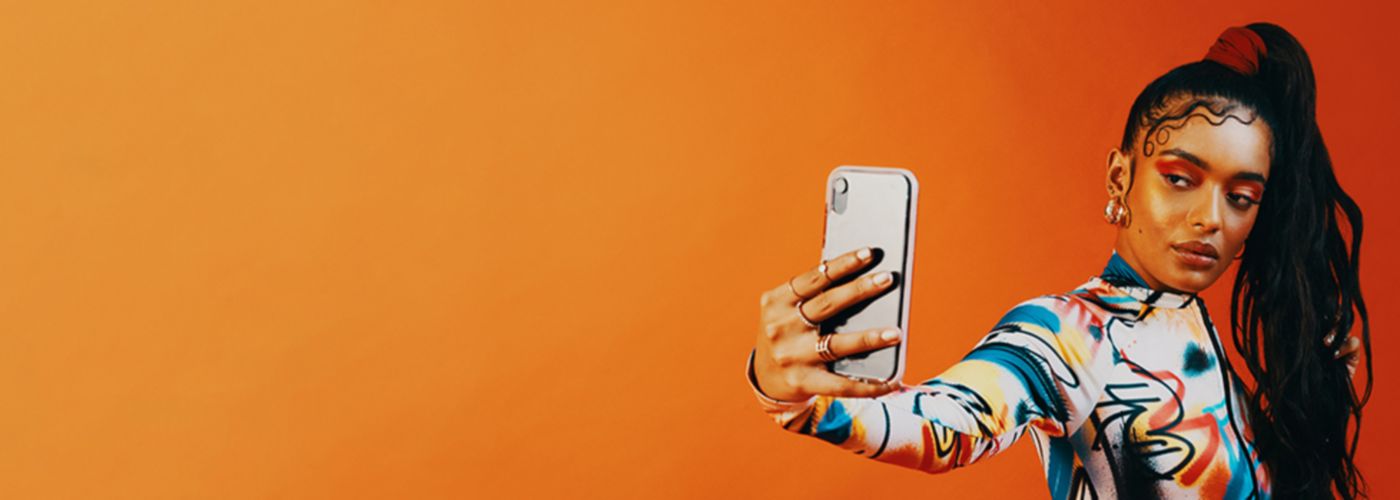 Woman taking selfie in front of orange background