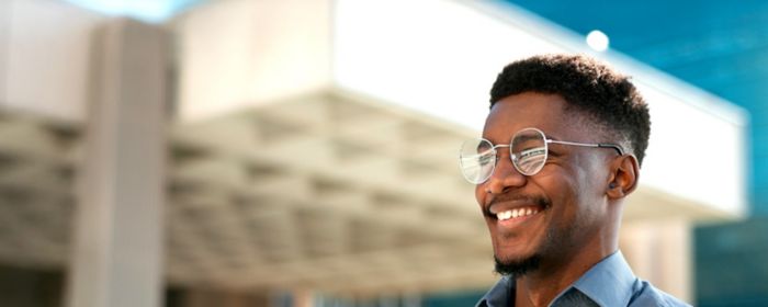 Man wearing specs smiling against office building