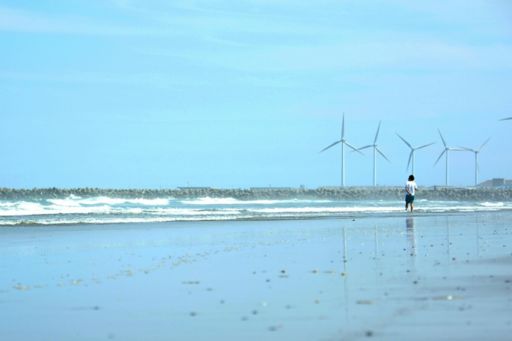 風車がある海岸に佇む男性