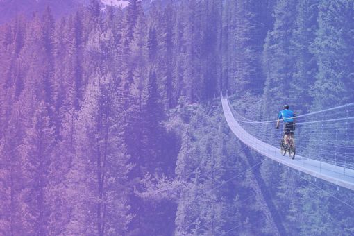 山の中のつり橋を自転車で渡る人