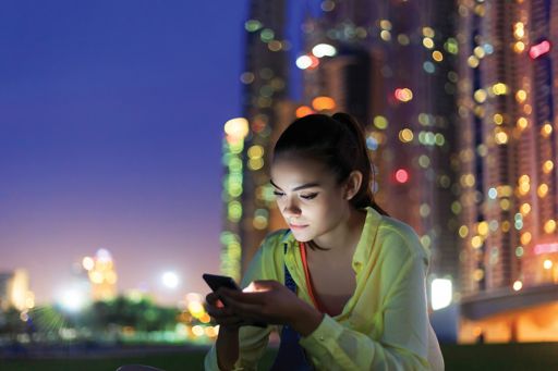 夜の屋外でスマートフォンを見る女性