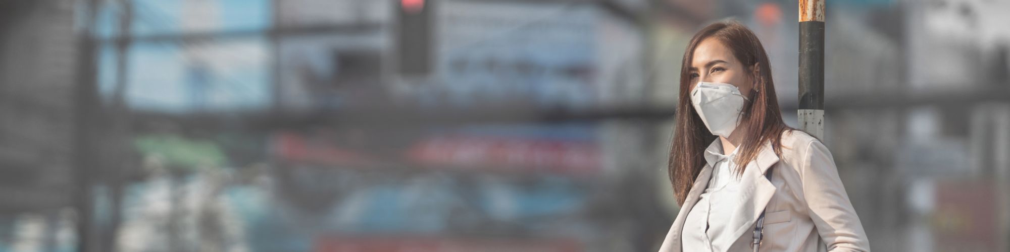 信号のある通りでたたずむパンツスーツの女性