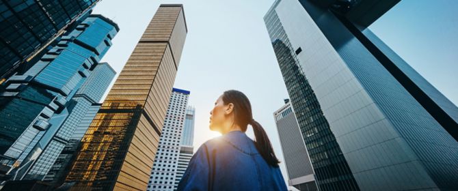 高層ビルと青空を背景に立つ女性