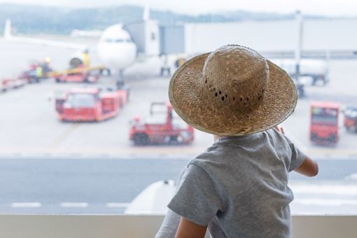 Kid wearing hat looking over airplane