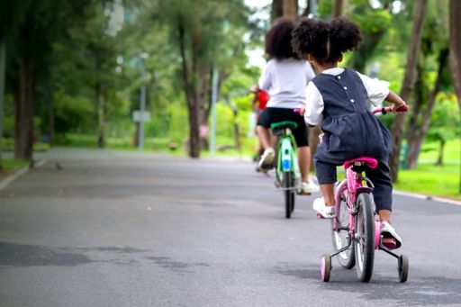 Children cycling through green parkland