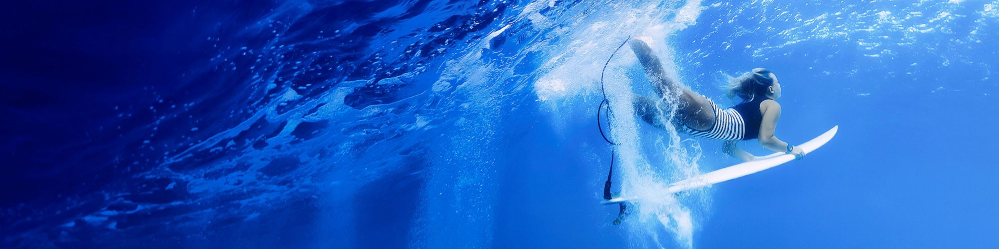 female surfer diving under wave