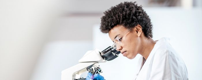 female researcher analysing on microscope