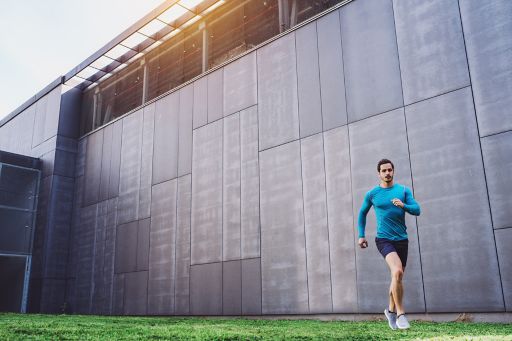 runner in front of concrete wall in blue shirt