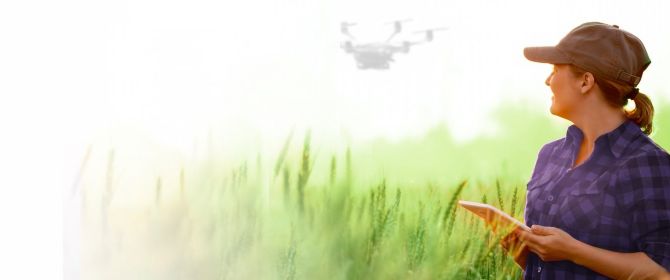 imagem uma mulher em uma plantação pilotando um drone